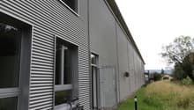 Metal cladding, glass windows, open door, bicycles, concrete path, metal pole, grassy area