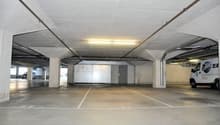 Underground parking lot with white concrete floor, white walls, concrete columns, bright lighting