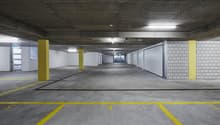 Large indoor parking garage with concrete floors, yellow painted lines and columns, and white tiled walls.