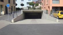 Underground parking lot with a ramp, metal railings, and a yellow car parked outside