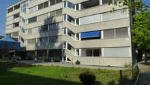Modern apartment building, many windows, terrace, outdoor area, parking, entrance area, bicycles parked