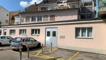 apartment building, multiple floors, 2 cars parked, grey metal poles in parking lot