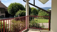 concrete floor, red metal railing, view of the yard and mountain