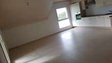 empty room with tiled floor, white walls, kitchen area with window, built-in appliances