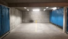 concrete walls, gray floor, yellow marking lines, blue plastic barriers, ceiling lights