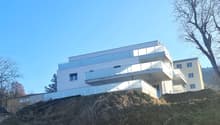 Modern design multistory house with glass balconies and terraces, white exterior, yellow walls, situated on a hill