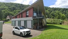 modern house, red wall, gray roof, glass windows, garage, large driveway, green grass, white car