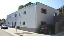2 story building, white facade, 6 windows, 2 cars parked in front and garage