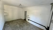 Unfinished basement or storage room with concrete floor, white walls, and a utility sink or basin on the wall.