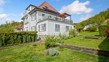 2 story house, white exterior, brown roof, balcony, solar panels, garden, bench