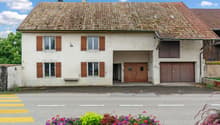 white house, brown tiled roof, brown wooden shutters, two garages, entrance