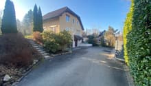 2 story house, beige walls, brown roof, paved driveway, front stairs, hedges, side gate