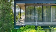 Modern design, large windows, metal railing, wooden floor, elevated position, greenery, and view of the surrounding area