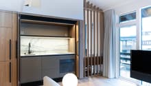 kitchenette with marble countertops, under cabinet lighting, pull out microwave and oven, sink with faucet, wooden cabinets, large window