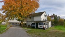 Single-family house, covered carport with two cars, tree in front, gravel driveway