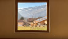 large window with view of mountains and houses