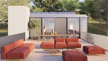 Modern outdoor living space with a terrace, solar panels on the roof, large windows, and a view of the surrounding landscape.
