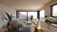 modern living room with large windows, wooden floor, white walls, large couch, coffee table, plants, wooden chairs, table with candles, kitchen with cabinets and countertop
