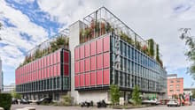 modern office building with red facades, glass windows, green roof, and modern architectural design