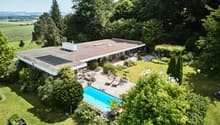 Modern house with flat roof, large swimming pool, garden, and solar panels