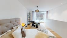 modern bedroom with a large bed, balcony, wooden floor, white walls, decorative items, and a view of the outside