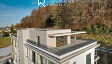 Two-story building with terrace on the second floor, glass windows, modern design, white exterior, trees, view of the hills