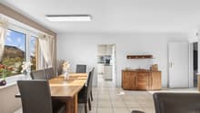 large windows, wooden dining table, chairs, wooden cupboard, bright kitchen