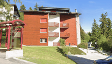 wooden and white building, 4 stories, balcony on each floor, tree-lined surroundings