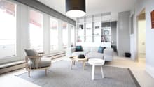 modern living room with white walls, large windows, wooden floor, gray rug, white couch, wooden chair, white coffee table, black pendant light