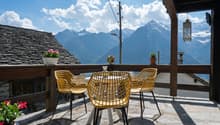 yellow chairs, round table, wooden railing, potted plants, mountain view