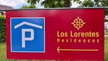 Red sign with blue and white parking symbol, text 'Los Lorentes Residences', arrow pointing right