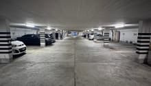 underground parking lot, white and black painted pillars, multiple parking spaces