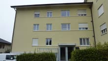3-story yellow building, multiple windows, entrance with glass doors, white van parked in front