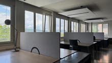 modern office with desks, chairs, lamps, large windows, gray walls, wooden floors