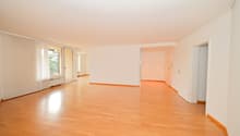 Empty room with wooden floors, white walls, sliding doors, and windows with white curtains