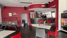 red wall, black tiled floor, counter with chairs, foosball table, two tables with chairs