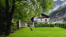 Two story house, wooden exterior, balcony, landscaped yard with shrubs and steps