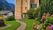 2 story house, brown brick, green shutters, garden, gravel path, mountain view