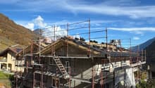 a two story house under construction, surrounded by orange fences and scaffolding