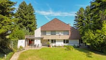 House with brown roof, white walls, large front yard, outdoor seating area, plants, trees, fence