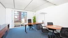 modern office room, white walls, blue carpet, wooden desks and chairs, large glass windows