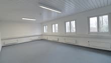 Empty room with white walls, ceiling and floor, six windows, heating radiators, ceiling lights