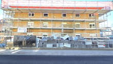 Building under construction, scaffolding, multiple windows, materials stacked in front