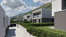 multiple story apartment complex, gray concrete exterior, underground parking garage, multiple outdoor terraces, raised ground floor, mountain view
