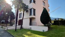 4 story apartment building, pink exterior, large windows, raised ground floor, palm trees, green lawn