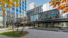 modern office building with glass facade, graveled outdoor seating area, glass covered entrance, greenery