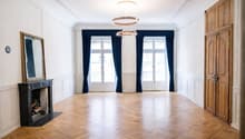 wide room, fireplace, hardwood floors, large windows, ceiling lamps
