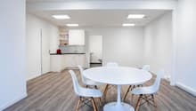 modern dining room with white round table, white chairs, light hardwood floors, modern kitchen, and built-in white cabinetry