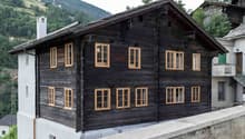 Traditional wooden chalet with yellow-framed windows, slate roof, chimney, mountain view