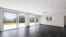 large sliding glass doors, black tiled floor, white walls, painting on wall, view of grassy area